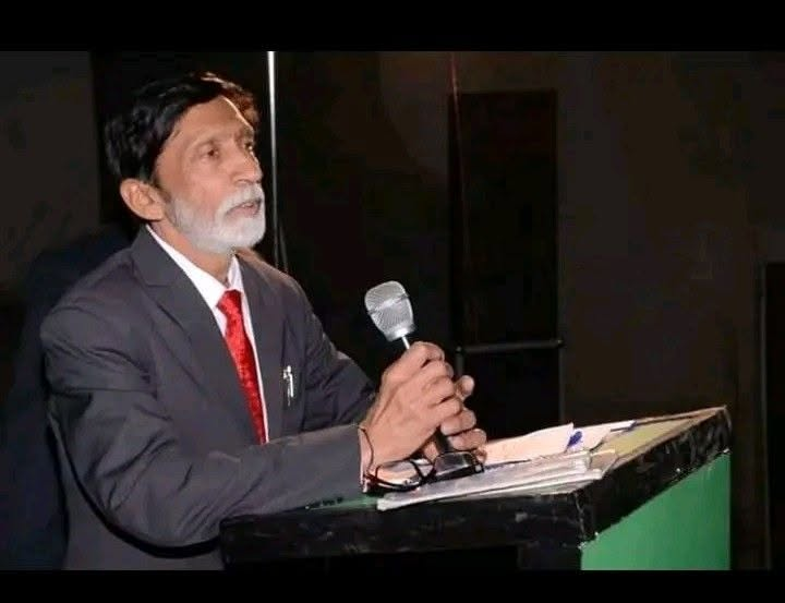 S.D. Singh Ratan speaking into a microphone at a lectern